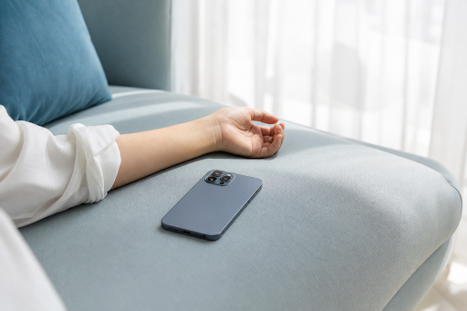 Person's-arm-rests- near-a-smartphone-on-a-sofa.